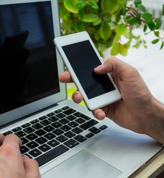 Hands of male executive using mobile phone and laptop