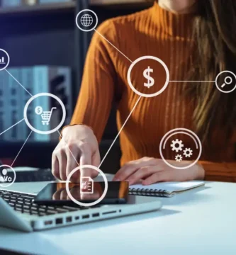 Persona revisando datos financieros en una tablet y laptop con íconos de crédito, pagos y analítica