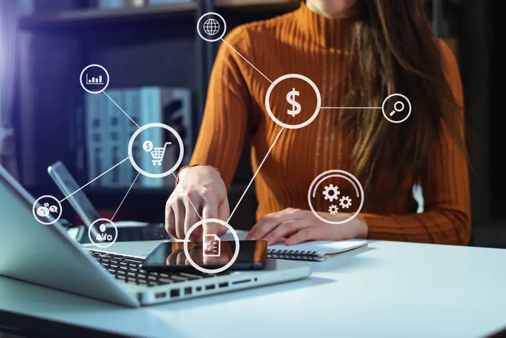 Persona revisando datos financieros en una tablet y laptop con íconos de crédito, pagos y analítica